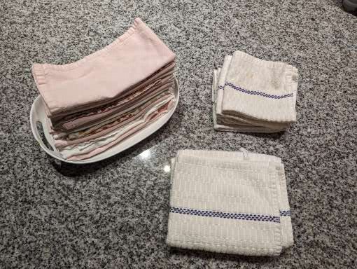 Left is a stack of cloth napkins. Right are cloth dish towels and cleaning towels.